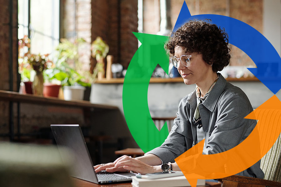 Woman sits at her desk and uses her laptop with a Conexon logo behind.