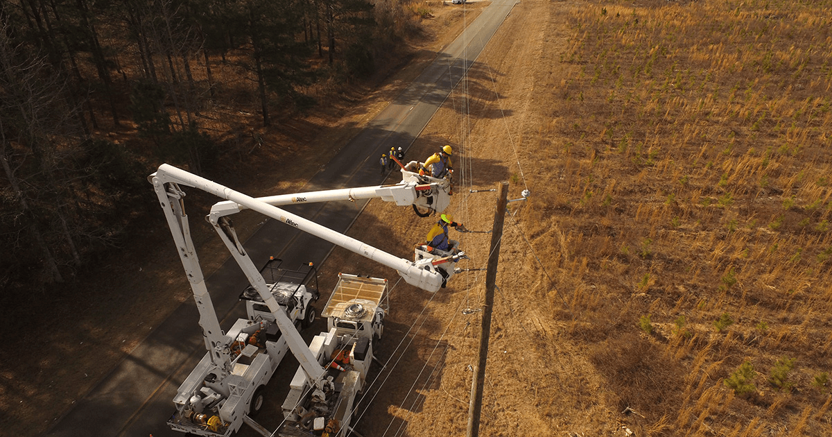 An arial shot of construction workers in a boom truck working on power lines.
