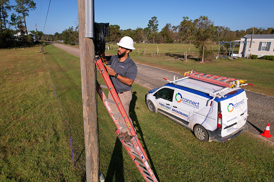 Service industry worker on a ladder working on a power pole.