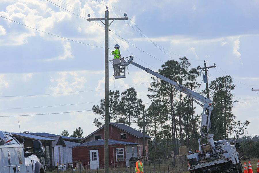 Service industry worker in a lift truck working on a power pole.