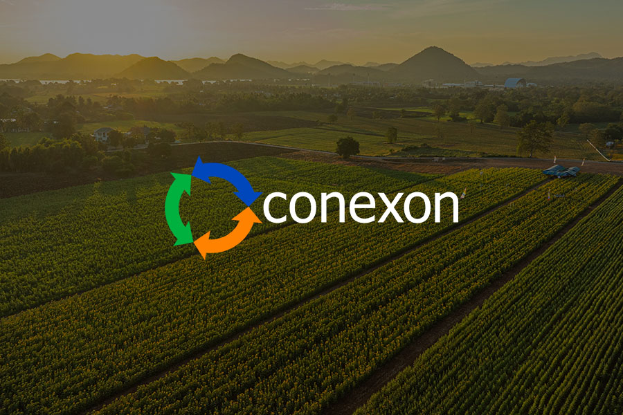 A rural area with a large crop field with mountains in the background at sunset with a Conexon logo.